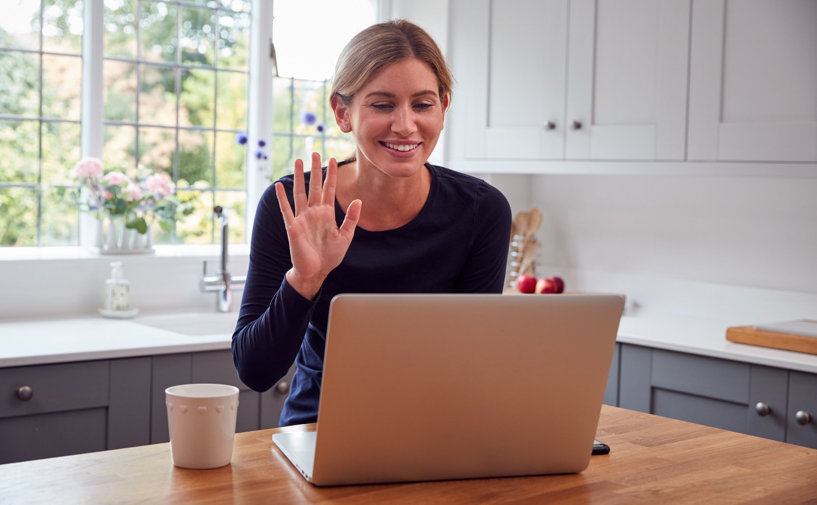 Woman in Kitchen Having Video Chat with Friend on Laptop Sitting